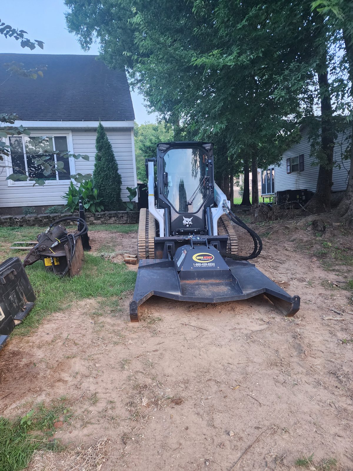 Bobcat T66 with the brush cutter mounted and the concrete breaker beside it
